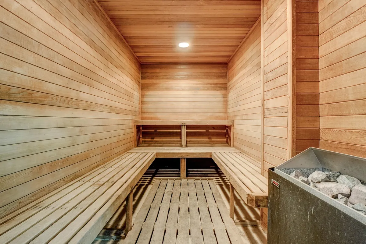 A tranquil sauna interior with wooden benches and a traditional stone sauna stove. Warm, natural wood paneling creates a serene and rejuvenating environment, inviting guests to unwind after a day of activities.
