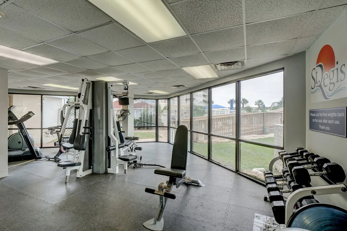 A spacious fitness center filled with modern exercise machines and weightlifting benches, bathed in natural light from large windows. The space feels motivational and energetic, inviting guests to maintain their fitness routines or recharge after work.