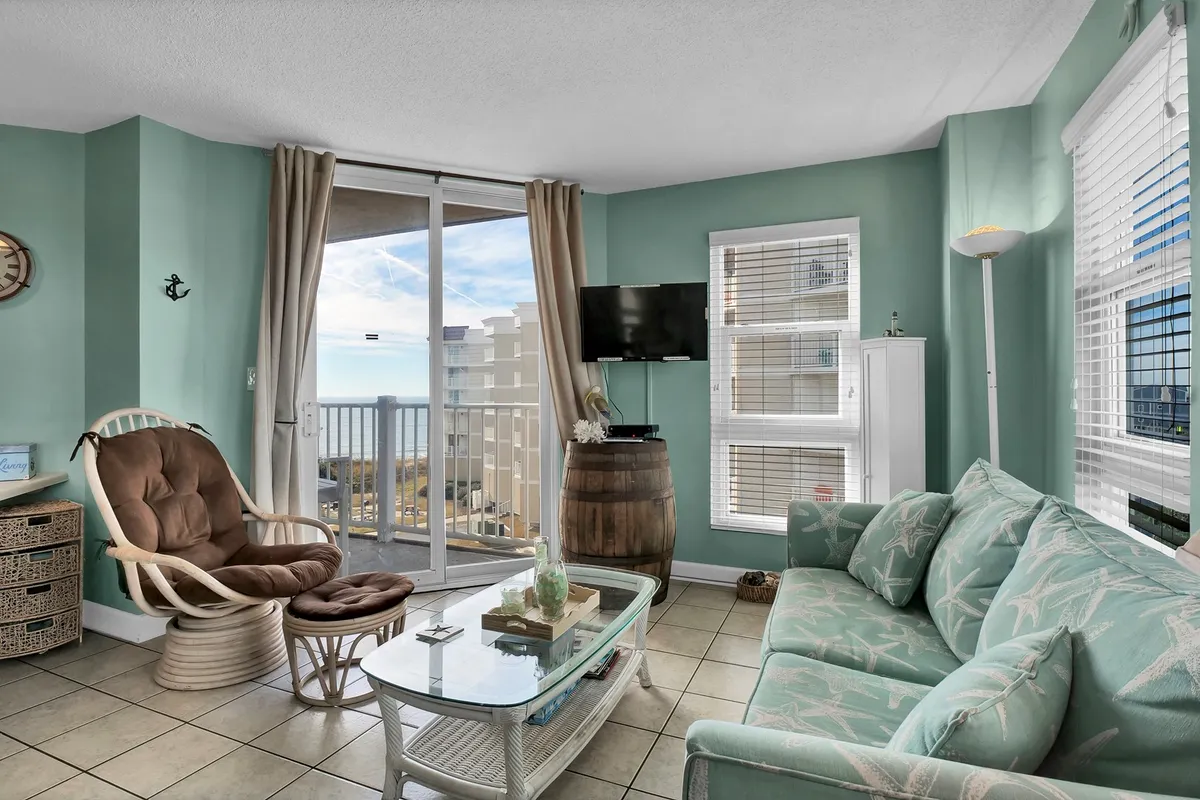 This cozy interior living area features large windows that frame a stunning ocean view, with comfortable seating positioned to take full advantage of the scenery. The space is filled with natural light, inviting guests to relax with a book or enjoy the tranquil backdrop of the waves.