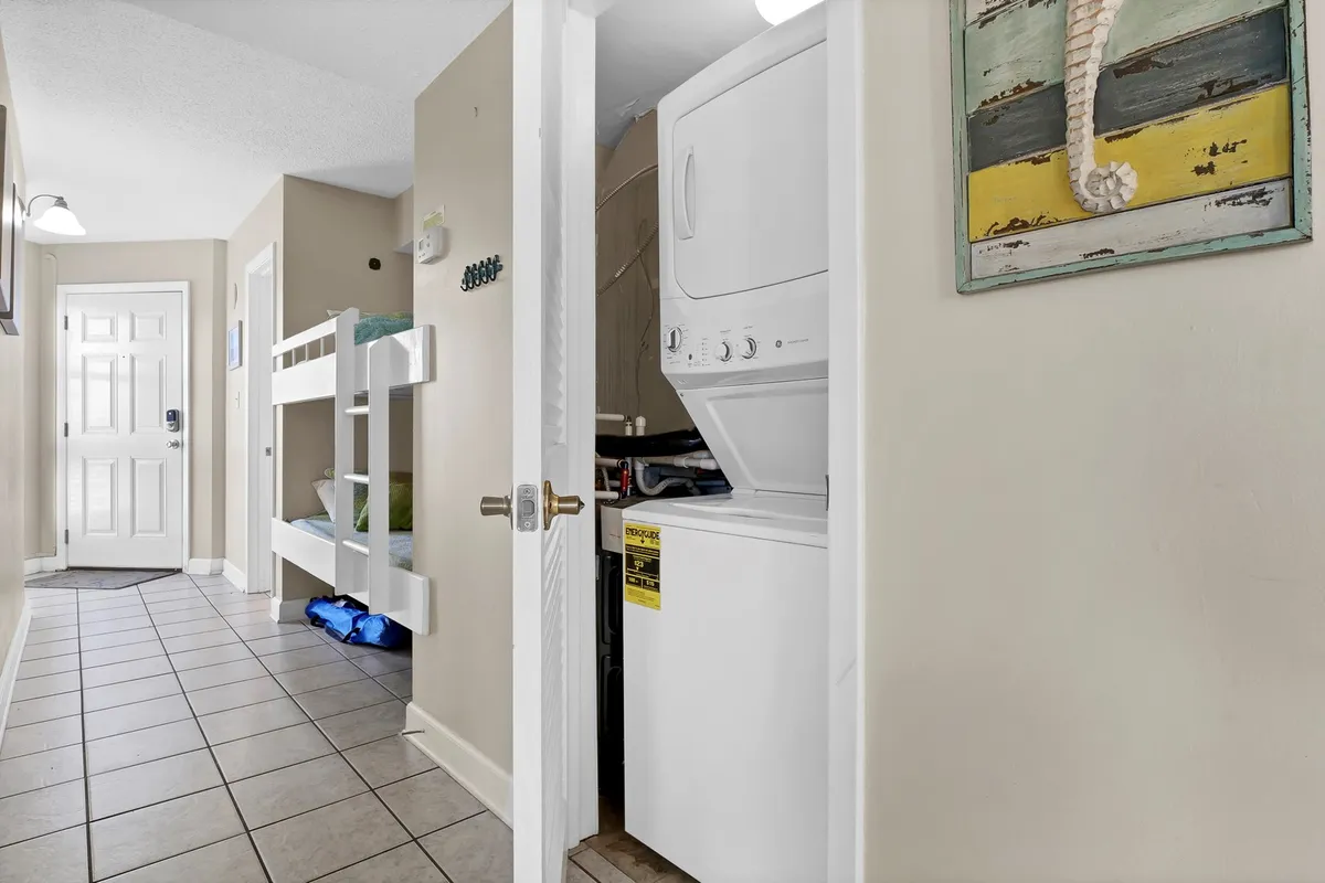 A practical interior scene showing a washing machine tucked near bunk beds and decorative wall art, blending convenience with family-friendly comfort.